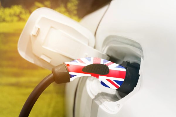 The concept of ecological transport. Charging an electric vehicle using an electric cable with a picture of the UK flag
